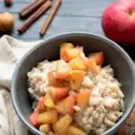 Diced apples sprinkled with cinnamon on top of oatmeal in a bowl.