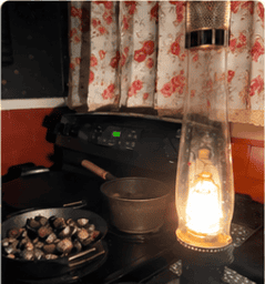 Woodstove, cast-iron cookware and oil lamp in a rustic homestead kitchen